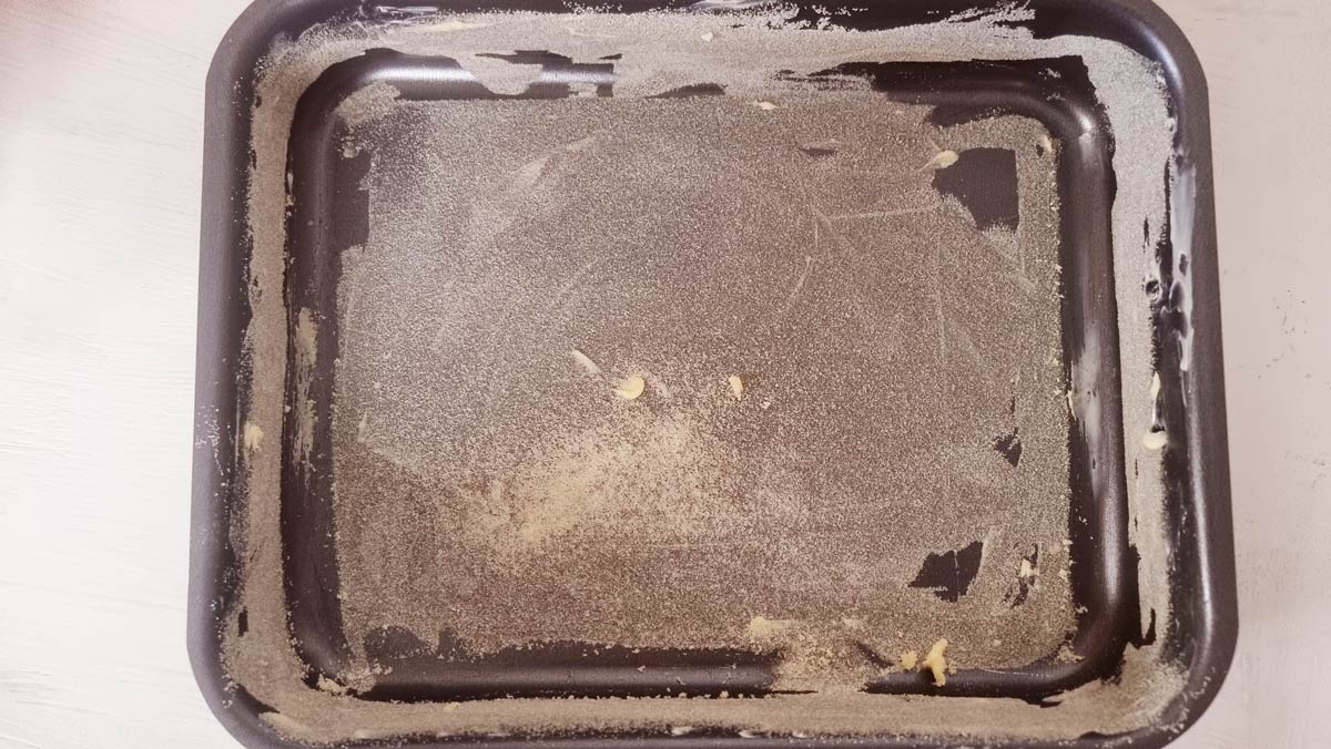 A baking pan greased with butter and dusted with fine semolina for making revani.