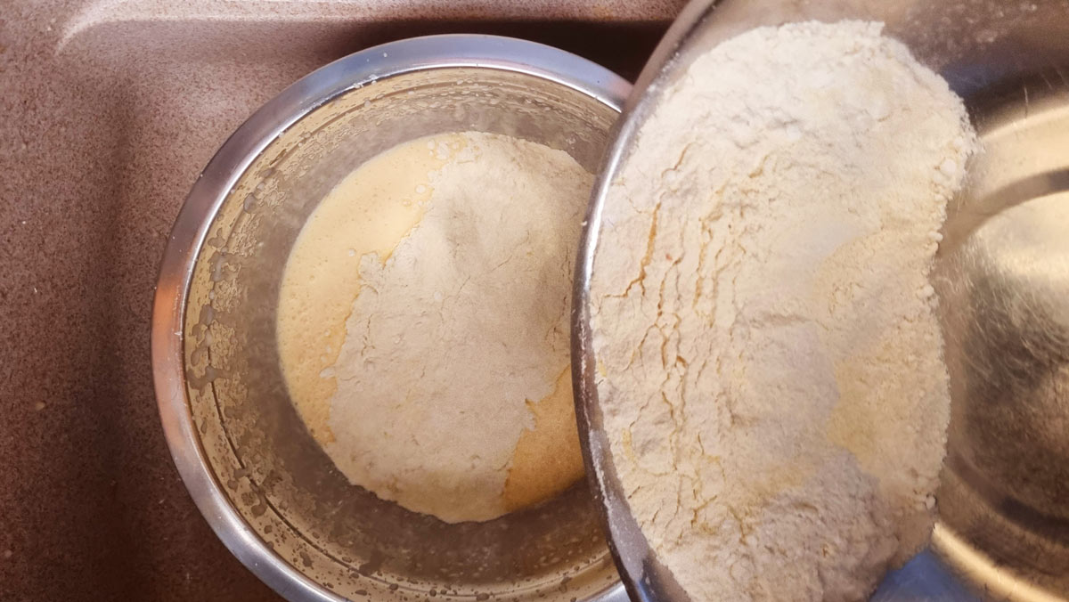 Adding dry ingredients to wet ingredients for making revani.