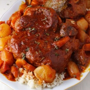 A featured image of Greek braised beef shanks on a platter served with rice.