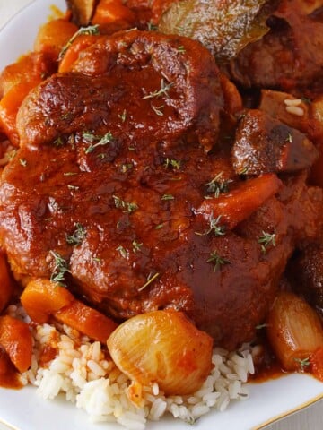 A featured image of Greek braised beef shanks on a platter served with rice.