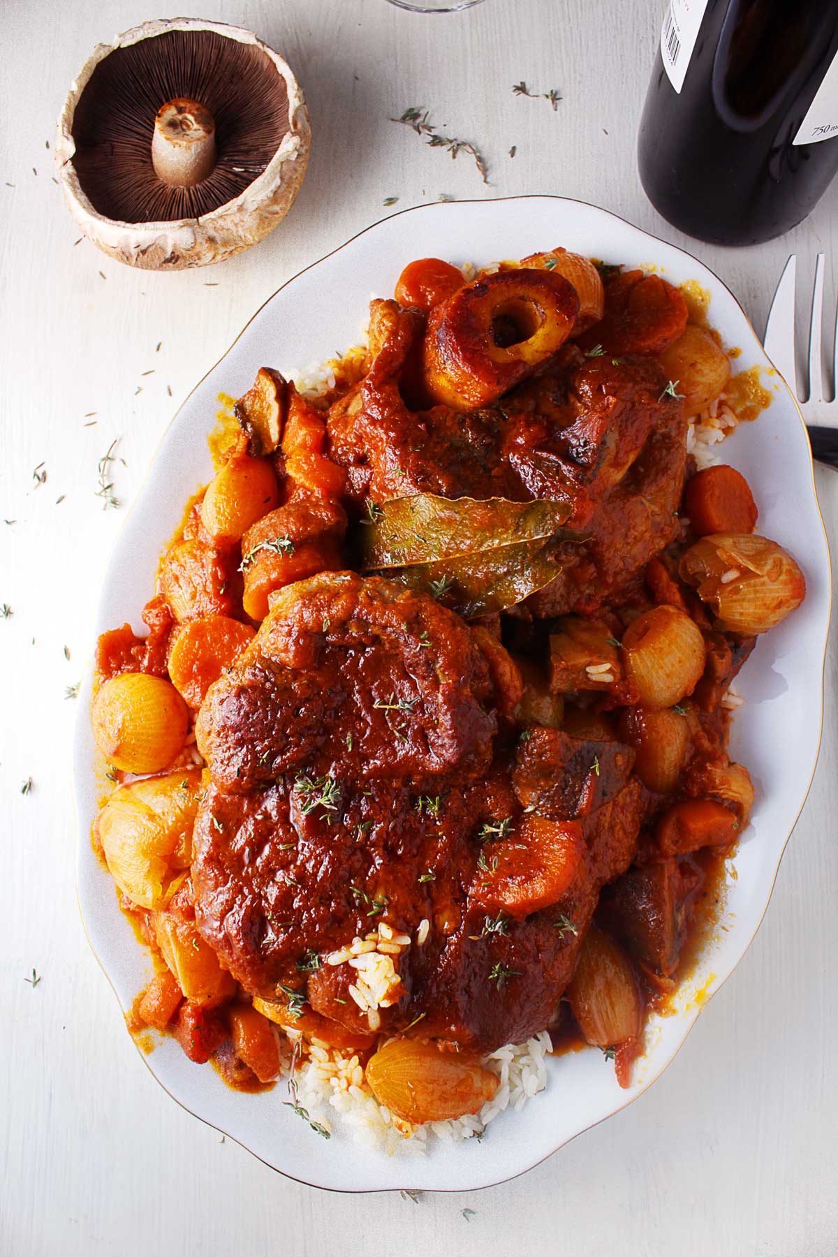 A on-top photo with a platter with braised beef shanks with shallots and mushrooms served with white rice.