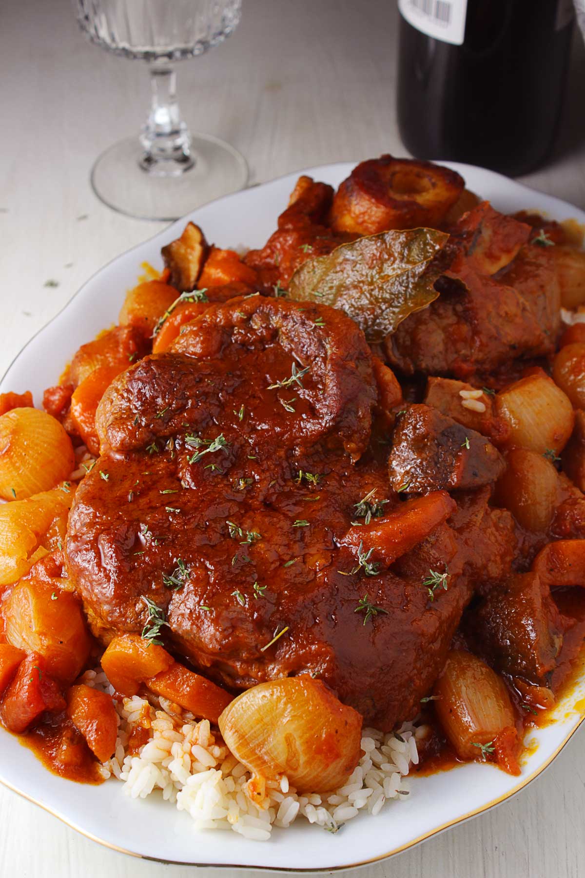 A close up photo of a platter with braised beef shanks with shallots served with rice.