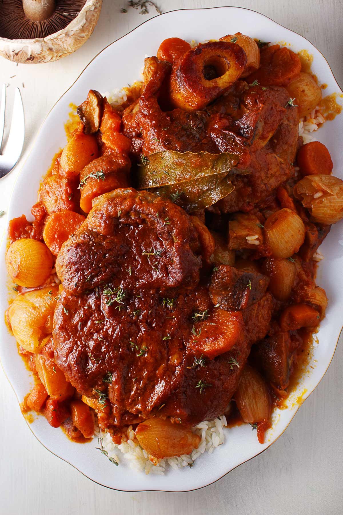 A white platter with Greek beef stifado served with rice.