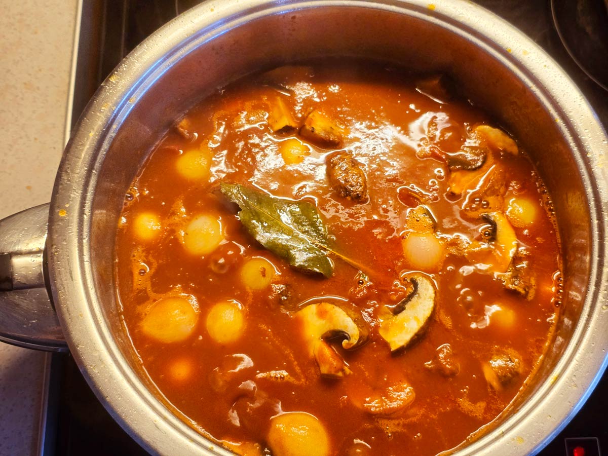 A pot with ingredients to simmer for making Greek beef shanks stifado.