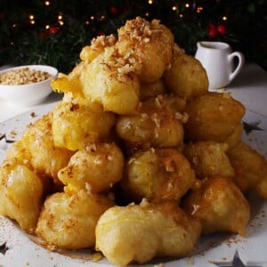 A feature image of a pile of Greek donuts (loukoumades) on a festive platter.