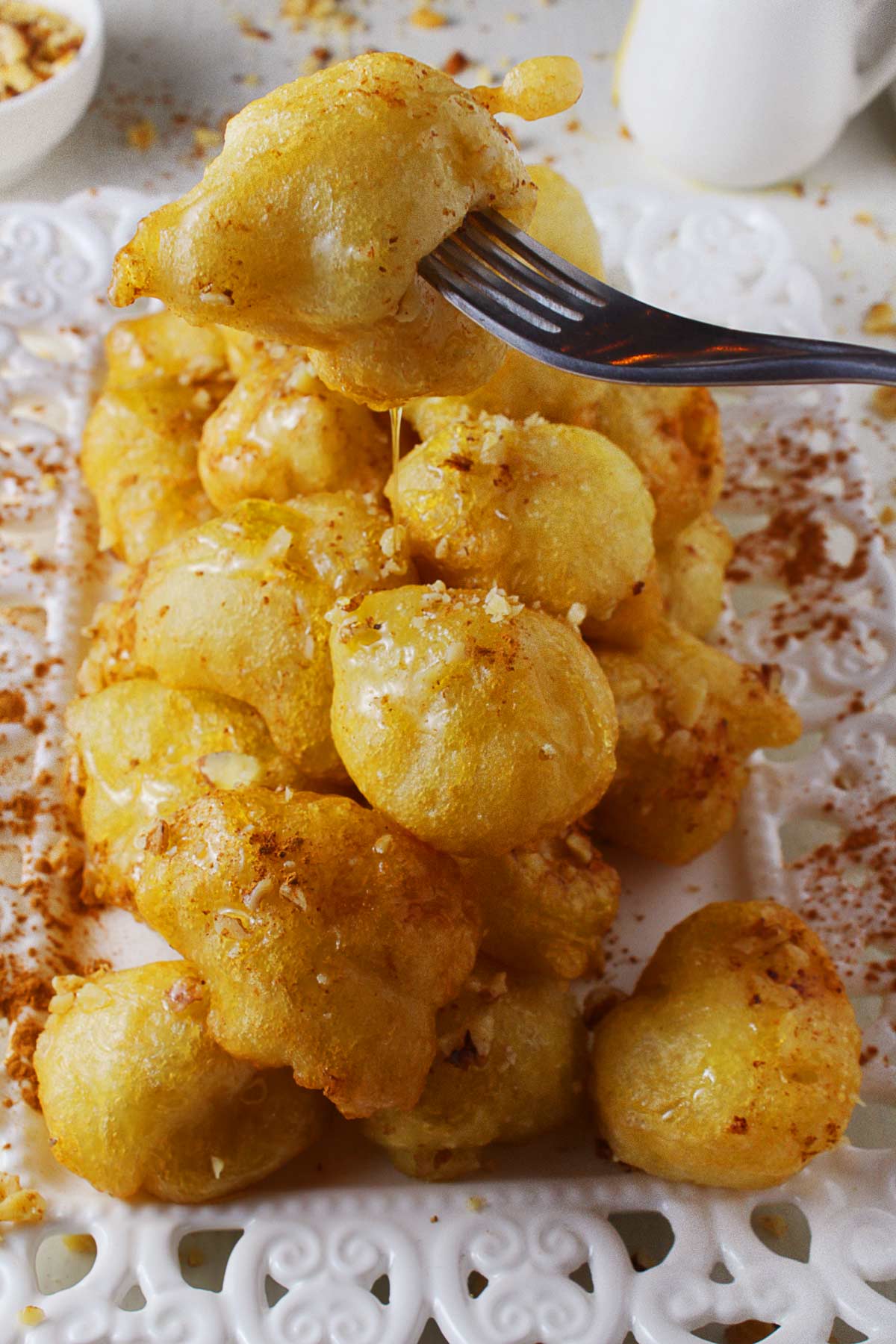 A fork with a loukoumades ball over a platter.