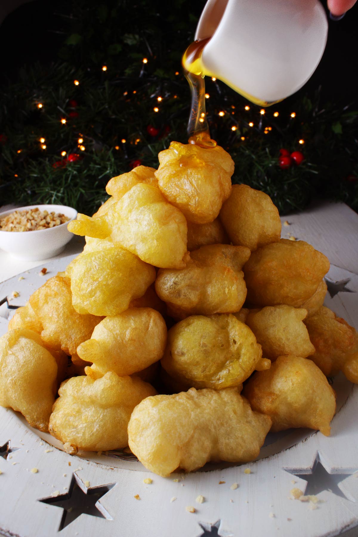 A pile of Greek donuts (loukoumades) in a festive Christmas platter.
