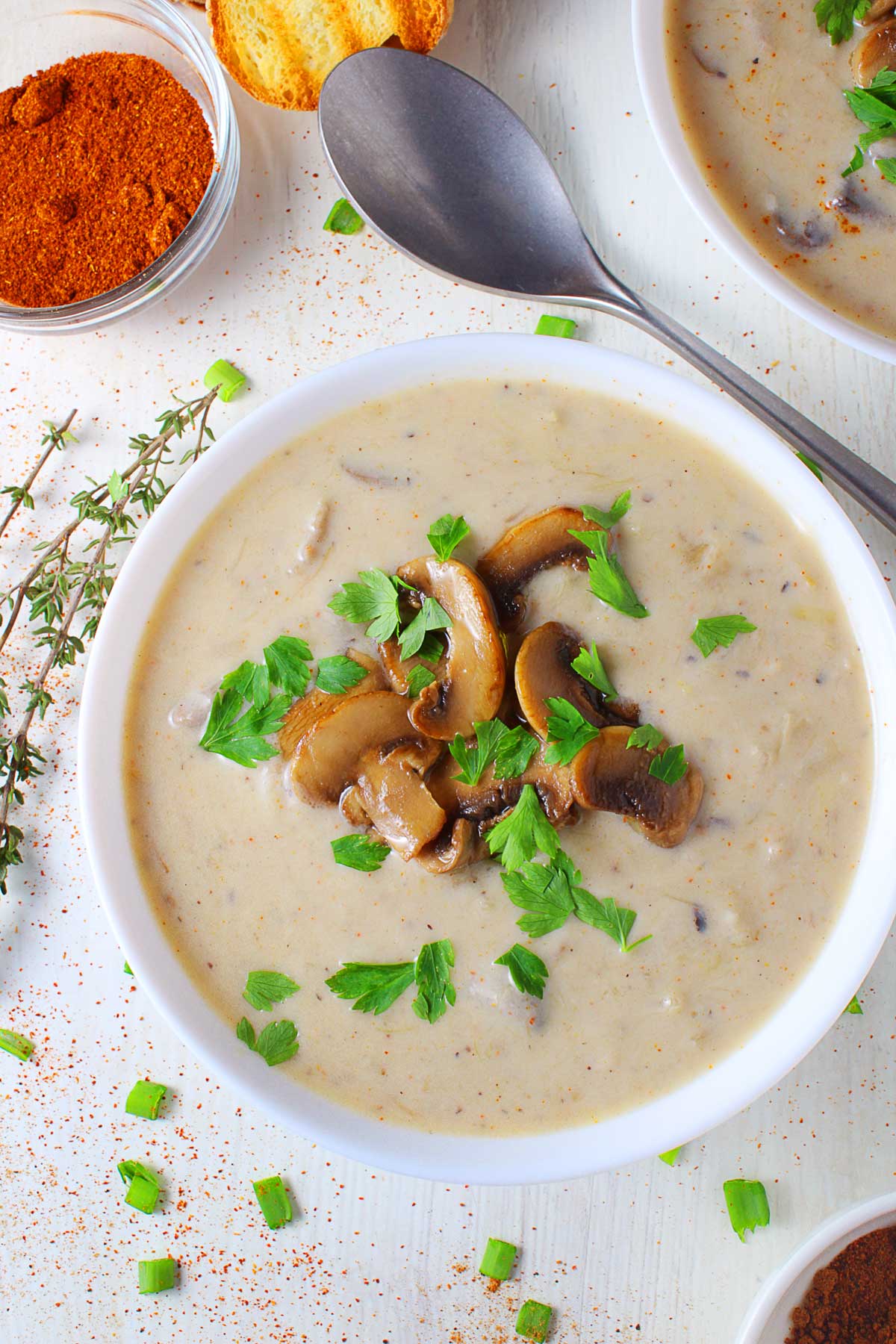 An n-op photo of a white bowl with mushroom and leek soup, topped with parsley.