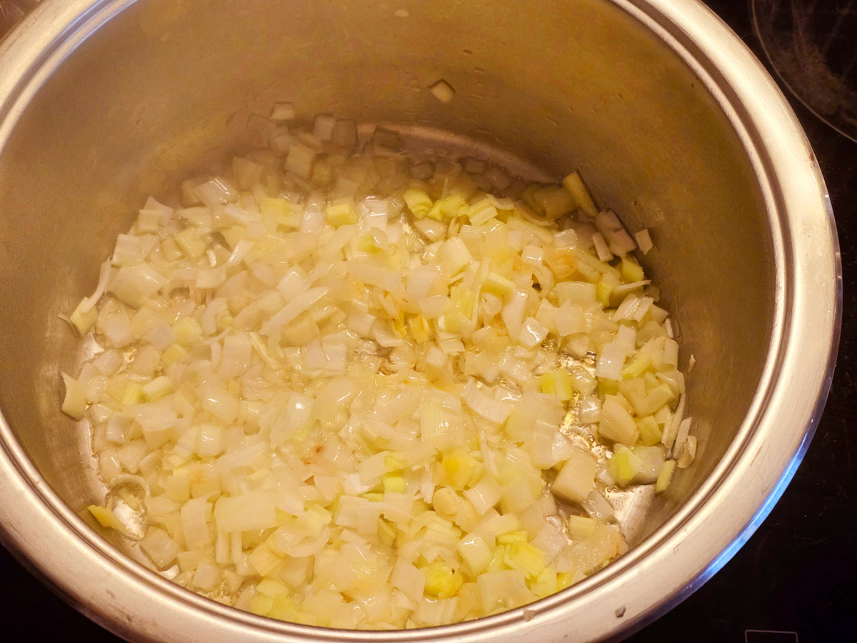 Sautéing chopped onions and leeks in a big pot.