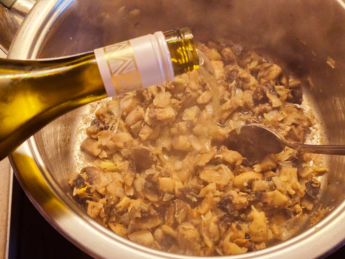 Deglazing a pot with mushroom and leek soup with white wine.