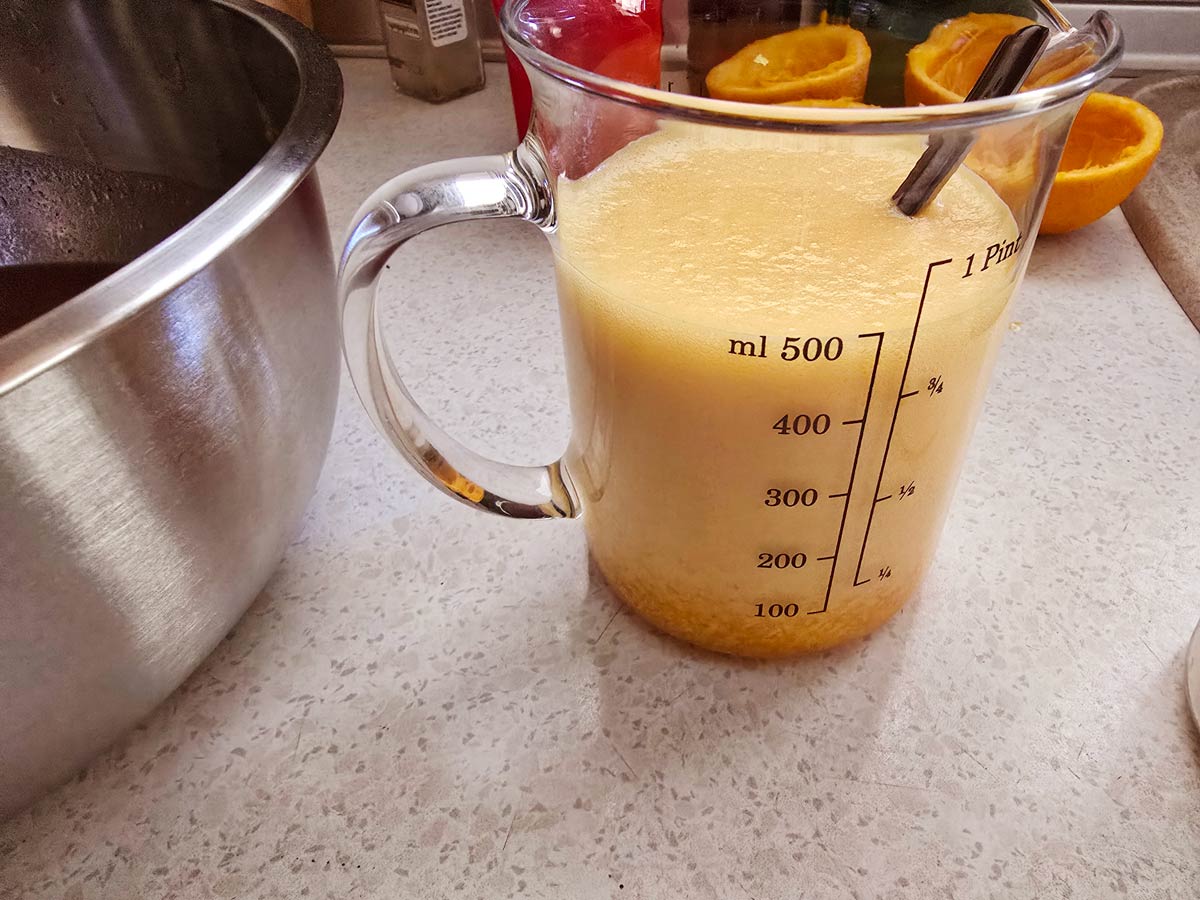 A jug with fresh orange juice foaming by the addition of baking soda.