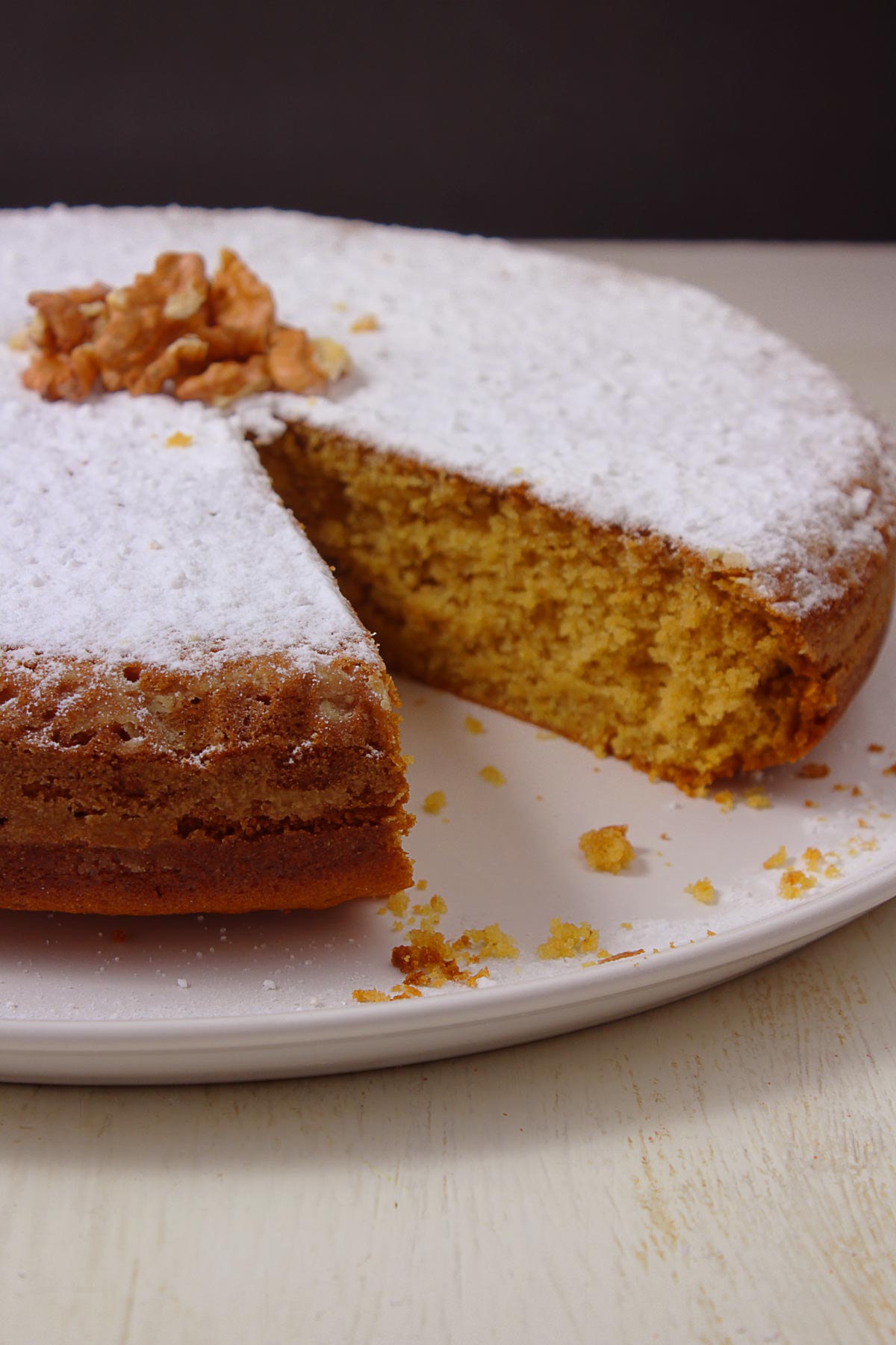 A Greek vegan cake (fanouropita) on a white round platter with a missing piece.