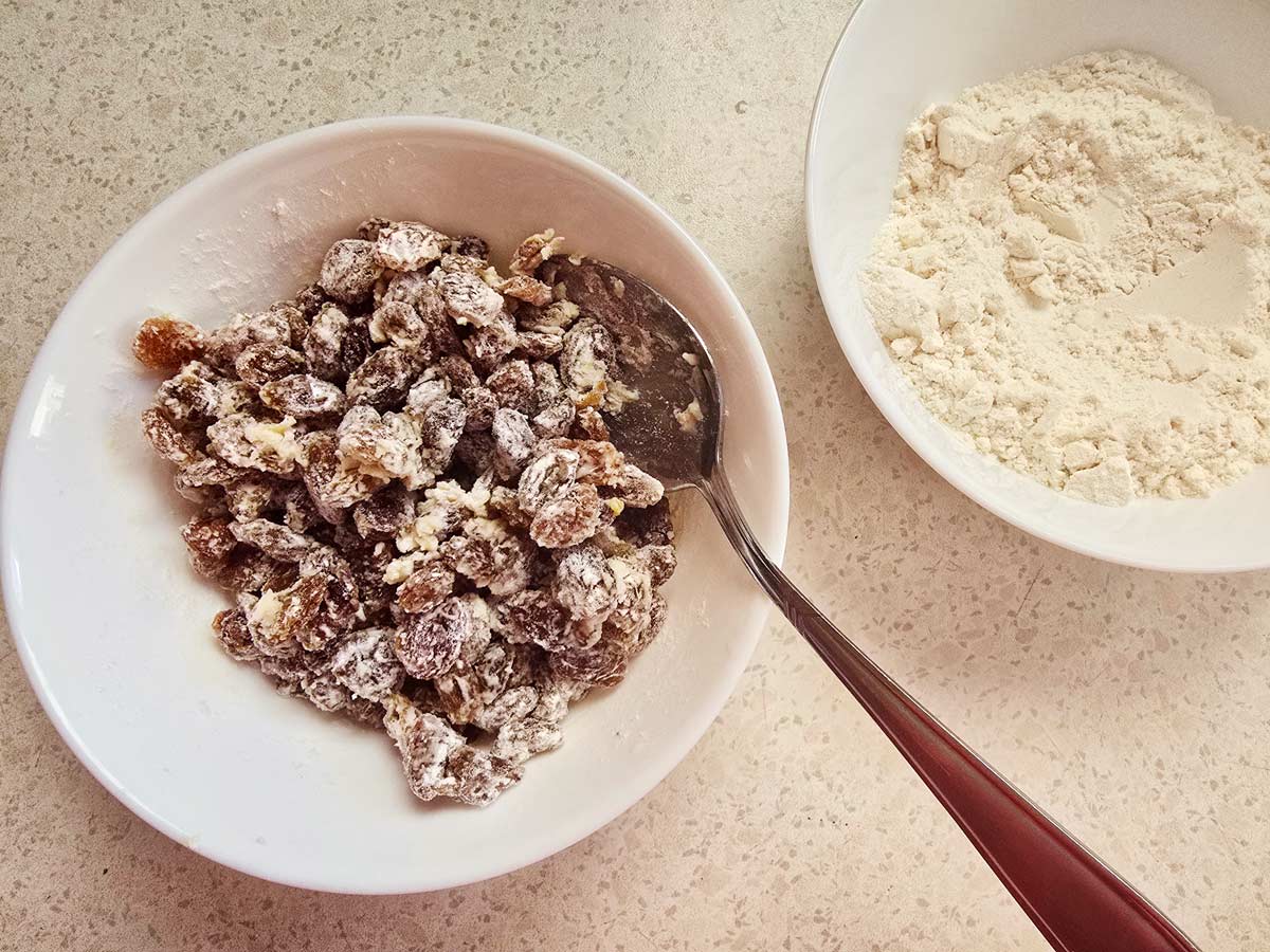 Raisins coated in flour in a small white bowl.