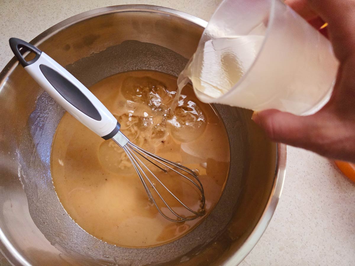 Pouring wine in a bowl with ingredients for Greek vegan cake.
